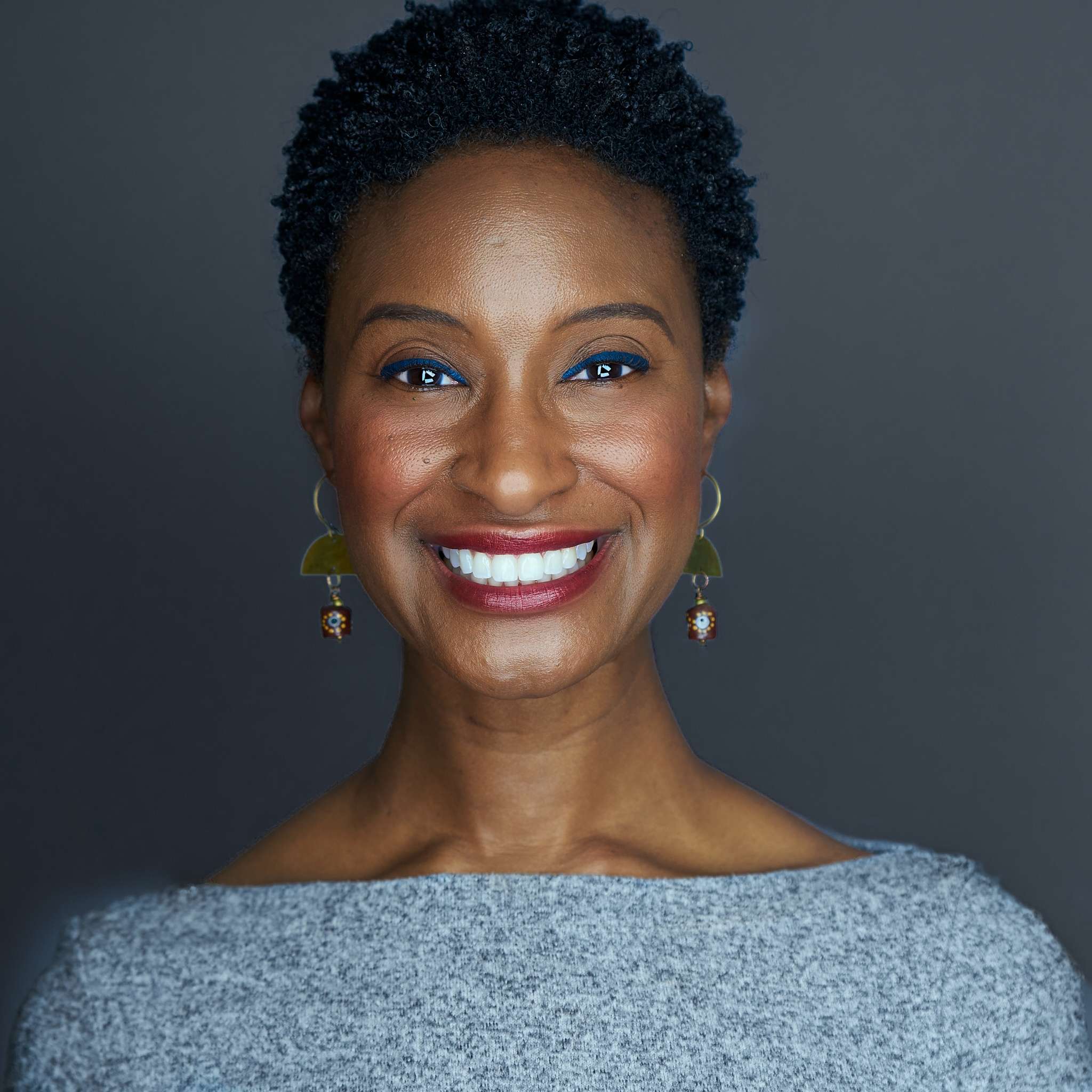headshot of founder Julye Williams, an African American woman with a short afro smiling against a dark grey background.